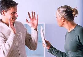 Couple arguing, a woman holding a paper while a man raises his hands defensively