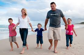 Parents and three children walking hand in hand along a beach