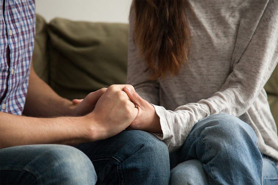 Two people sitting close together, holding hands