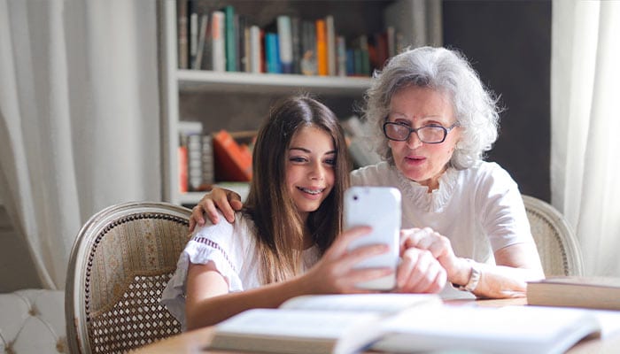 elderly woman looking at phone with her granddaughter