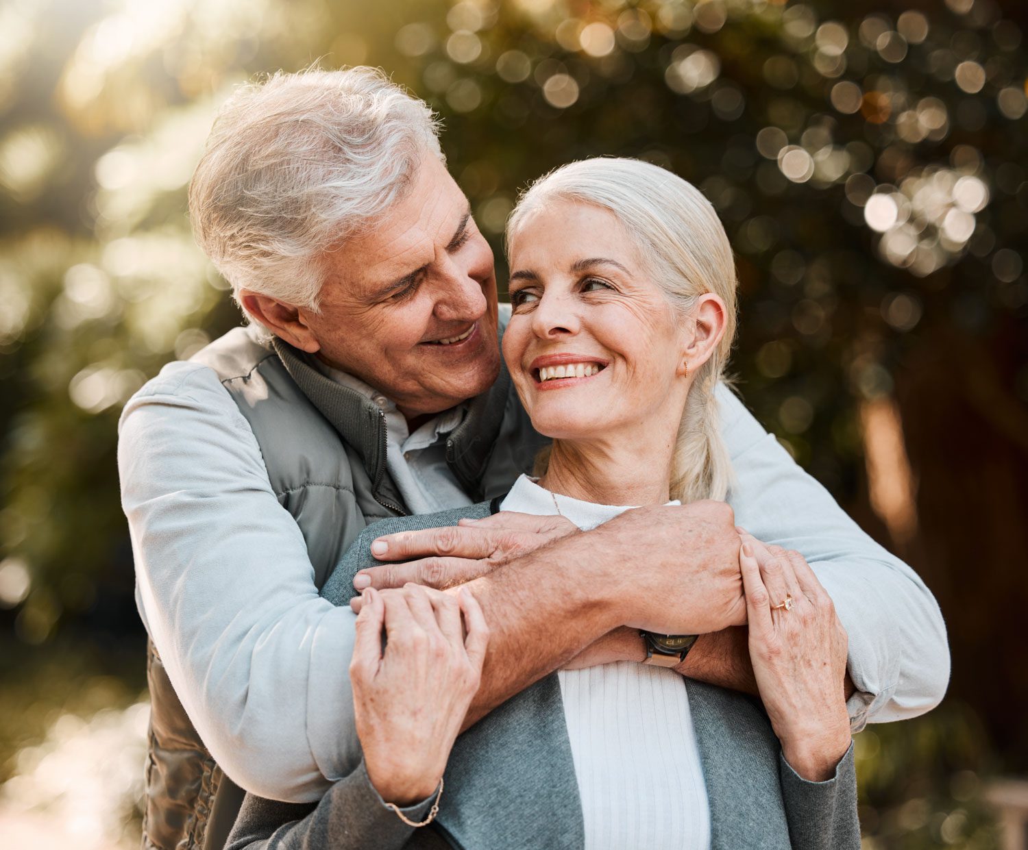 Love,,Hug,And,Senior,Couple,At,A,Park,Happy,,Free Love, hug and senior couple at a park happy, free and enjoy travel, holiday or weekend outdoor. Face, smile and elderly man embrace woman in forest, bond and having fun on retirement trip together